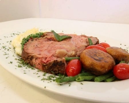 Plated prime rib with side of green beans and mushrooms